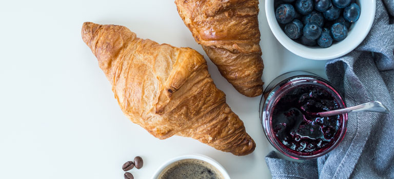 Französisches Butter-Croissant serviert mit frischen Blaubeeren und fruchtigem Gelee