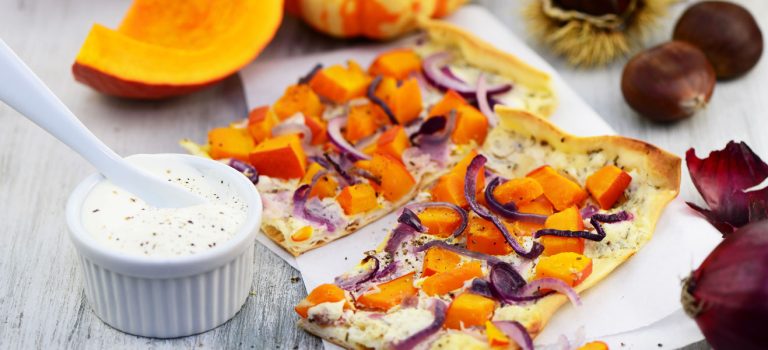 Kürbis – Ein nahrhafter Koloss Mit Crème Fraîche bestrichener Flammkuchen und Kürbisspalten sowie roten Zwiebeln als Belag